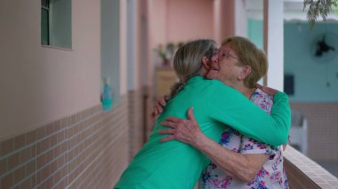 Sıcak bir aile buluşması, yetişkin bir kızın yaşlı bir anneyi kucaklaması. Nesil kucaklaşması, yaşlı bayanın akrabaları tarafından ziyaret edilmesi.