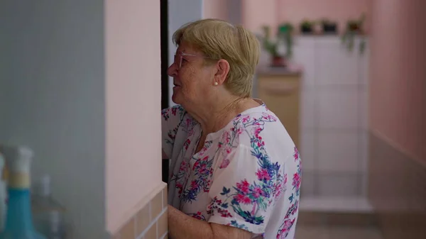 一位80多岁的老年妇女背着墙走在家里的走廊上 家庭生活方式方面的老年人 — 图库照片