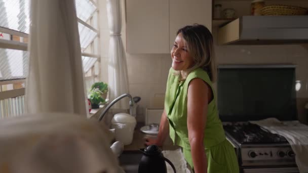 Neşeli Orta Yaşlı Bir Kadın Mutfaktaki Pencerenin Önünde Durmuş Mutlu — Stok video