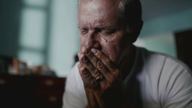 Utanç ve endişeyle yüzünü kapatan dalgın yaşlı bir adam. Kafkas kökenli orta yaşlı bir erkek çaresizlik içinde saklanarak hayatın zorluklarıyla mücadele ediyor.