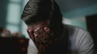 Utanç ve endişeyle yüzünü kapatan dalgın yaşlı bir adam. Kafkas kökenli orta yaşlı bir erkek çaresizlik içinde saklanarak hayatın zorluklarıyla mücadele ediyor.