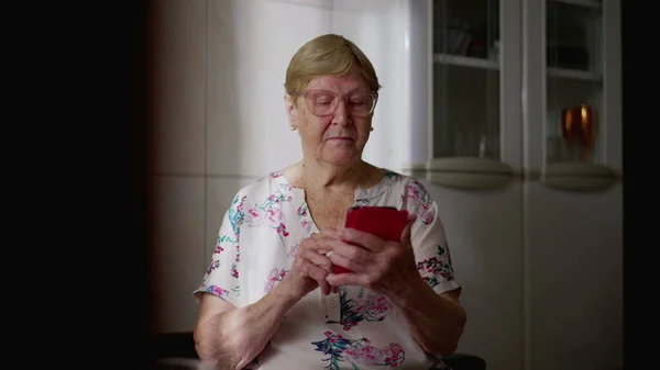 家庭で携帯電話を使用して技術的に精通した高齢者の女性 現代技術とオンラインブラウジングに従事シニア女性 — ストック写真