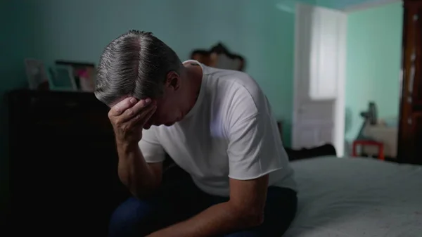 stock image Anxious preoccupied older man sits by bedside feeling worry. Stressed desperate middle-aged person feeling suffering from mental illness