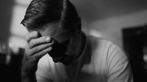 stock image Older man struggling with trauma and loneliness. Middle-aged male person covering face looking down in shame and despair. Hopeless feeling depicted in monochrome black and white