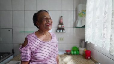 Mutfak penceresinin yanında durup bakan neşeli son sınıf kadını. Yüzünde mutlu bir ifade olan siyahi Afrikalı bir Amerikalı.
