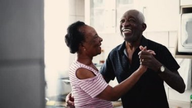 Mutlu yaşlı çift mutfakta dans ediyor. Siyahi bir Afrikalı Amerikalı karı-koca arasında romantik bir an.