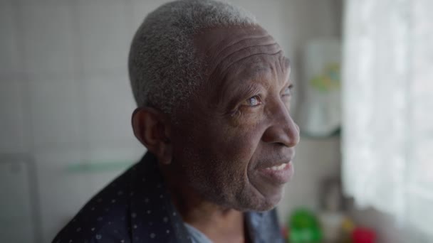 一个任性的资深非裔美国人站在厨房的窗边 一个有着沉思沉思表情的老年黑人男性的近视脸 — 图库视频影像