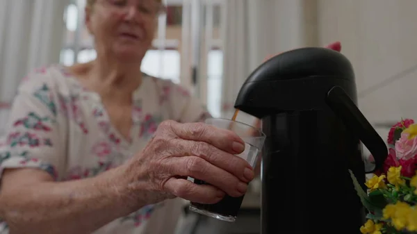 老年妇女按压热水瓶顶部倒入玻璃杯咖啡 南美洲白种人老年人在咖啡店服务 — 图库照片