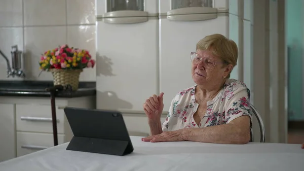 タブレット端末で親戚と話すシニア女性 ビデオ会議を通じて家族と話すために現代技術を使用して80年代の高齢者 — ストック写真