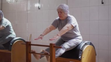 Yaşlı bir kadın pilates sınıfında vücut esnetiyor. Yaşlılık sağlığı ve refah içinde egzersiz yapan kıdemli kişi.