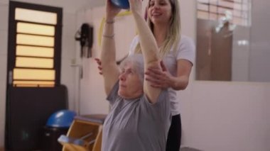 Yaşlı Çift Pilates Topları, Arkadaş Egzersizi Kadın Koçun Desteğiyle Yaşlılık Egzersizleri sırasında vücudun güçlendirilmesi