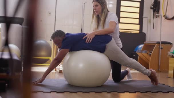 Physiotherapeutin Führt Schwarze Afroamerikanische Seniorin Zum Training Mit Pilates Ball — Stockvideo