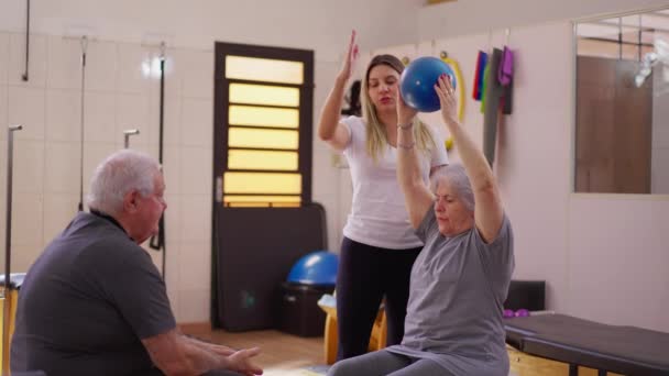 在女教练的协助下 在普拉提加强老年夫妇的锻炼 上了年纪的夫妻传球 — 图库视频影像