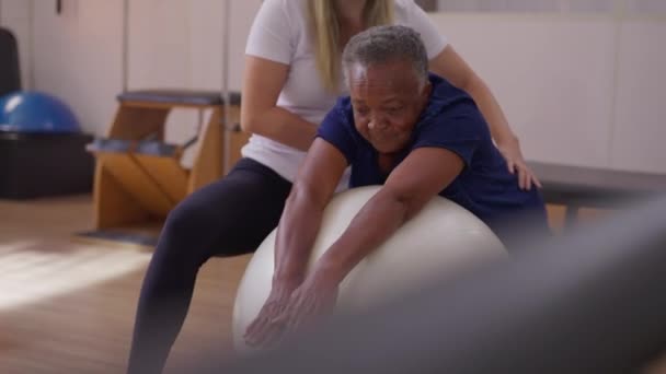 Kobieta Fizjoterapeuta Przewodnik African American Senior Woman Pilates Ball Ćwiczenia — Wideo stockowe