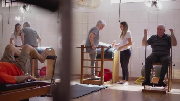 Kvinnliga Pilates Coach Hjälpa Senior Grupp Klass Sjukgymnastik Rehabilitering Äldre — Stockvideo