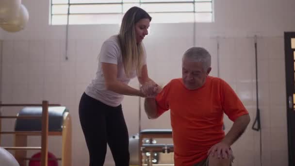Trenerka Pomaga Starszemu Mężczyźnie Wstać Podłogi Fizjoterapeuta Pomaga Starszej Osobie — Wideo stockowe