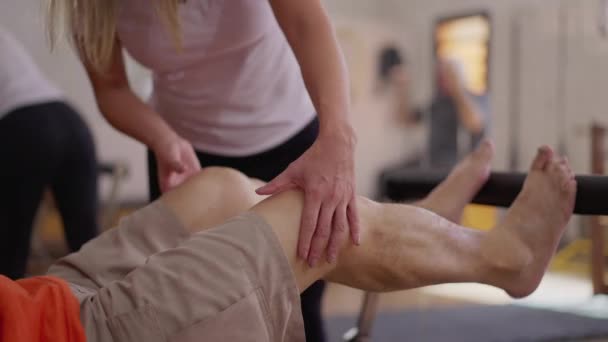 理疗师指导病人加强腿运动及使用普拉提机促进健康 — 图库视频影像