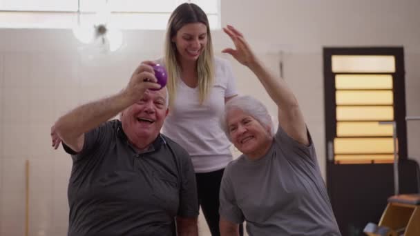 年纪较大的夫妇在一名女教练的指导下 在普拉提课上锻炼 年事已高的妻子和丈夫通过体育和幸福 在真正的关系中通过舞会传递 — 图库视频影像