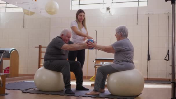 Elderly Couple Passing Each Other While Sitting Pilates Balls Companionship — Stock Video