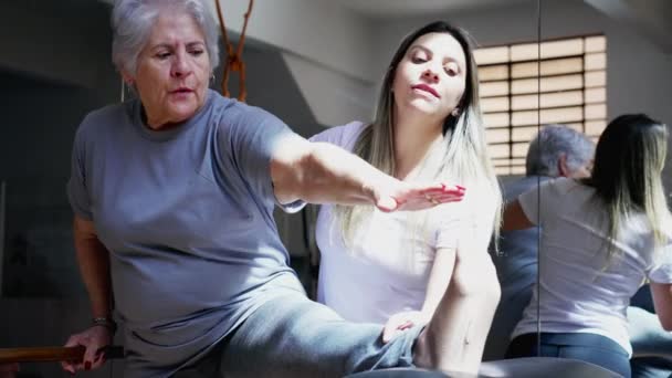 Kobieta Pilates Trener Pomaga Starszej Kobiecie Rozciągnąć Nogi Sesji Fizjoterapii — Wideo stockowe
