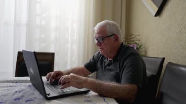 Evde dizüstü bilgisayar kullanan son sınıf öğrencisi. Bilgisayarda yazı yazan, internette gezinen yaşlı bir beyaz erkek.