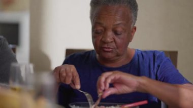 Yaşlı siyah bir kadın yemek yiyor, samimi bir son sınıf öğrencisi öğle yemeği yiyor. Yaşlılık emekliliği