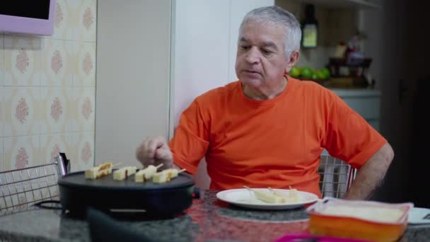 Senior Man Bereidt Kaasstokjes Met Elektrische Grill Thuis Keukentafel Oudere — Stockvideo