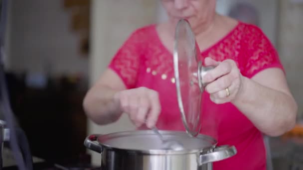 快乐的老年女士在厨房做饭 友善快乐的老年女士做饭 坦率而真实的生活方式 — 图库视频影像