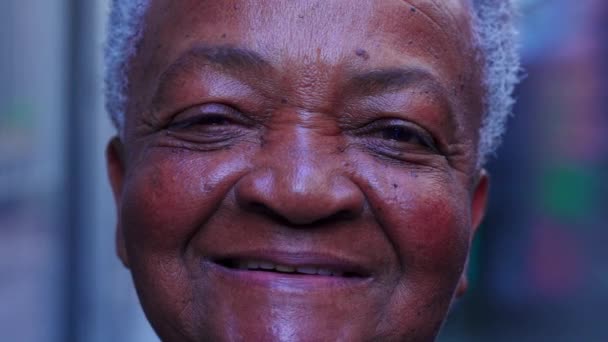 カメラで笑っている幸せなブラジルの先輩女性のマクロクローズアップ フレンドリーなカリスマ的表現を持つ楽しいアフリカ系アメリカ人のおばあさんの肖像 — ストック動画