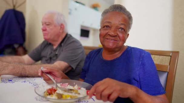 Μια Χαρούμενη Μαύρη Ηλικιωμένη Γυναίκα Χαμογελάει Στην Κάμερα Ενώ Τρώει — Αρχείο Βίντεο