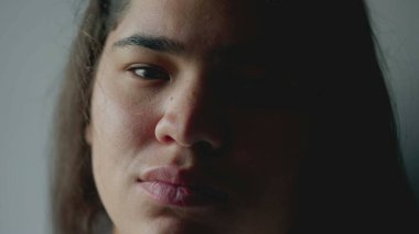 Ciddi bir ifadeyle kameraya bakan etnik çeşitliliğe sahip genç bir kadının yakın çekimi. 20 'li yaşlarda Brezilyalı bir Güney Amerikalı yetişkin kız