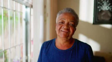 Mutlu bir siyahi son sınıf öğrencisi kameraya bakıp gülümsüyor. Brezilyalı, Afrikalı, Amerikalı, yaşlı, neşeli, yakın plan yüzü olan bir kadın.