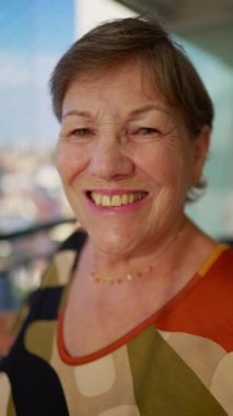 Kameraya gülümseyen yaşlı ve mutlu bir kadının yakın çekim yüzü. 70 'li yaşlarda beyaz bir kadının portresi.