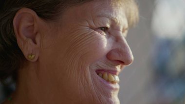 Neşeli ve dalgın gülümseyen mutlu bir son sınıf kadınının profilini çıkar. 70 'li yaşlarda mutlu bir insan pencereden dışarı bakıyor.