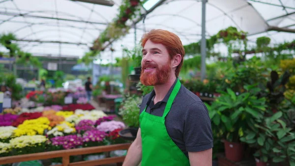 stock image Happy redhead Young entrepreneur walking through Flower Shop. A male business Florist owner of Plant Store strolling through Horticulture environment