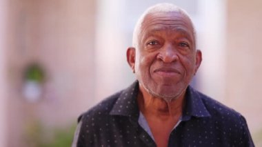 Nötr bir ifadeyle kameraya bakan siyahi üst düzey bir adamın portresi. 70 'li yaşlarda Afrikalı Amerikalı yaşlılar