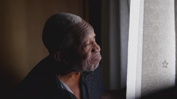 Przemyślane Spojrzenie Zamyślonego Czarnego Brazylijskiego Starszego Mężczyzny Stojącego Przy Oknie — Wideo stockowe