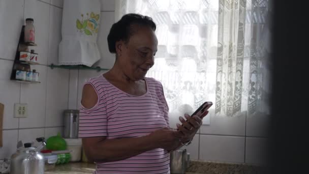 Candid Mulher Afro Americana Sênior Segurando Telefone Enquanto Estava Cozinha — Vídeo de Stock