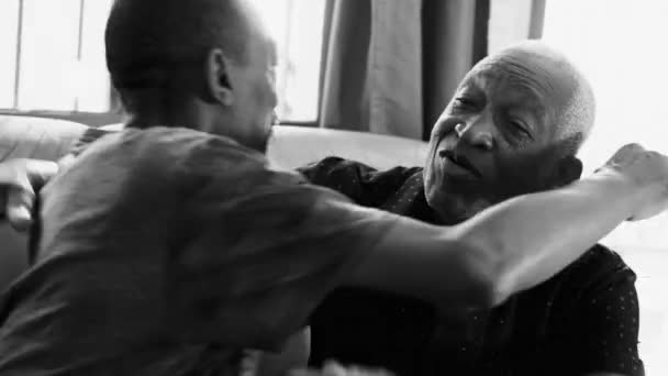 非洲裔美国人父亲将成年儿子抱在沙发上 用黑白单色表达爱和支持 — 图库视频影像