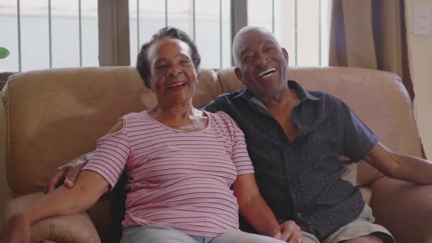 一对快乐的老黑人夫妇坐在沙发上笑着 一个年事已高的丈夫牵着妻子的画像 真真切切地笑着 — 图库视频影像
