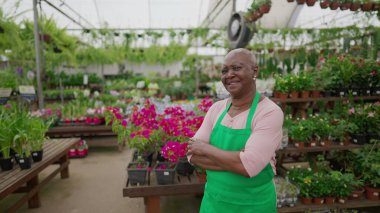 Yerel Çiçekçi Dükkanı 'nda kameraya poz veren Afro-Amerikalı yaşlı bir kadının portresi. Yeşil önlük giyen siyahi, üst düzey bir bayan çalışan.