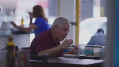 Son sınıfların gizli sahnesi Diner 'da öğle yemeğinin tadını çıkarıyor, daha yaşlı kişiler yemek molasında.