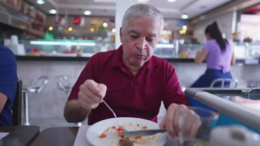Lokantada yemek yiyen, düşünceli bir ifadeyle öğle yemeğinin tadını çıkaran son sınıf öğrencisi.