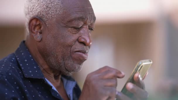 一位年长的黑人男子带着智能手机在网络媒体上打转 坦率的非裔美国老年人热衷于现代技术 — 图库视频影像
