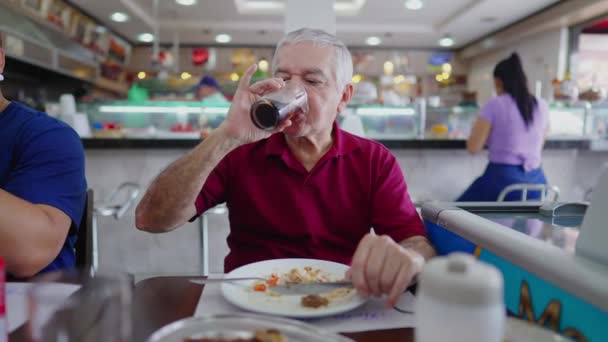 ブラジルの伝統的な食堂で食事を楽しむカジュアルな白人シニア男性 レストランでの高齢者の個人的な食事と飲み物ソーダ砂糖飲料 — ストック動画