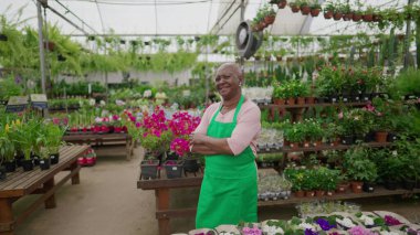 Neşeli Brezilyalı Çiçekçi, Tecrübeli ve kendini işine adamış bir işçi, Çapraz Silahlarla Yerel Çiçekçi Dükkanında Duruyor