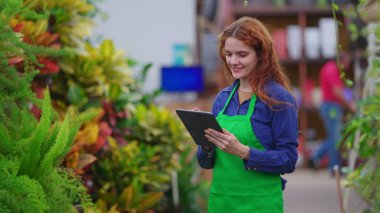 Satış mağazasındaki envanteri inceleyen mutlu bayan yönetici. Tablet cihazıyla Ticaret Dükkanı adasında yürüyen genç bir kadın.