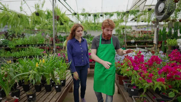 フラワーショップ内の女性顧客に花と植物を示す男性従業員 地元のビジネスコンセプト — ストック写真