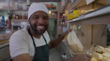 Bir siyah Brezilyalı yemek dükkanında çalışıyor fırının arkasında ekmek alıyor.