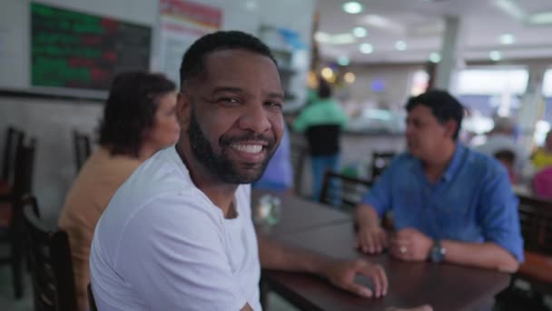 Счастливый Бразилец Улыбается Камеру Сидящую Ресторане Друзьями Человек Поворачивается Лицом — стоковое видео